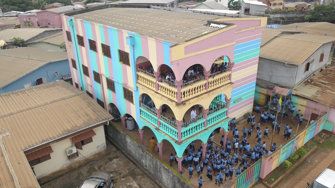 Vue aérienne du bâtiment à arcades de Nzeng Ayong, élèves dans la cour
